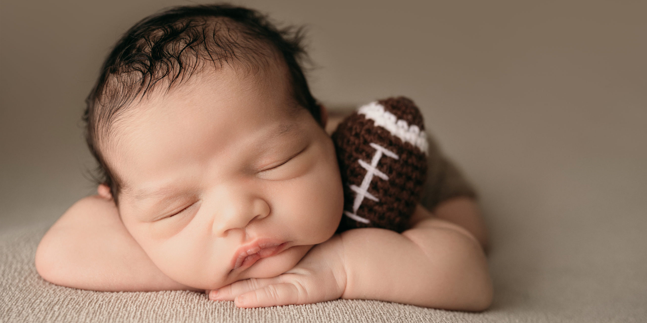 newborn boy holding football picture