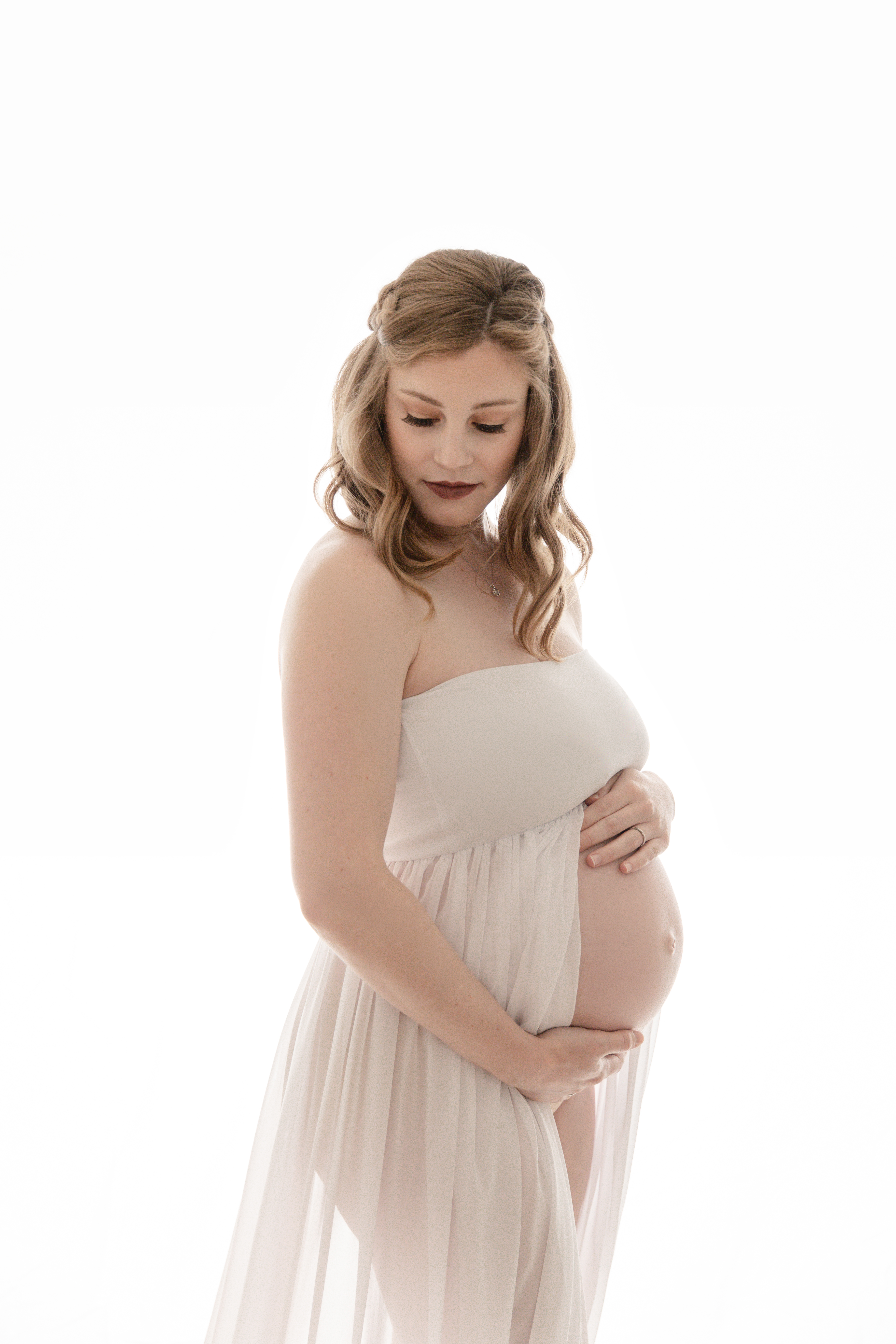 a pregnant maternity model infront of a white backdrop
